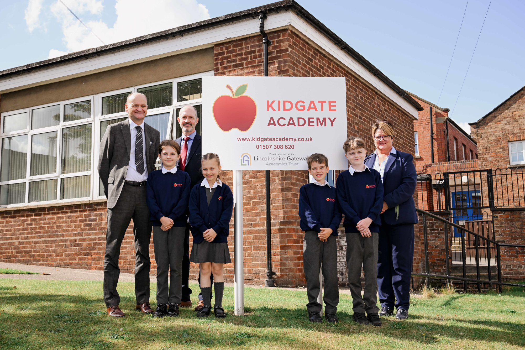 Staff and students standing next to new sign.